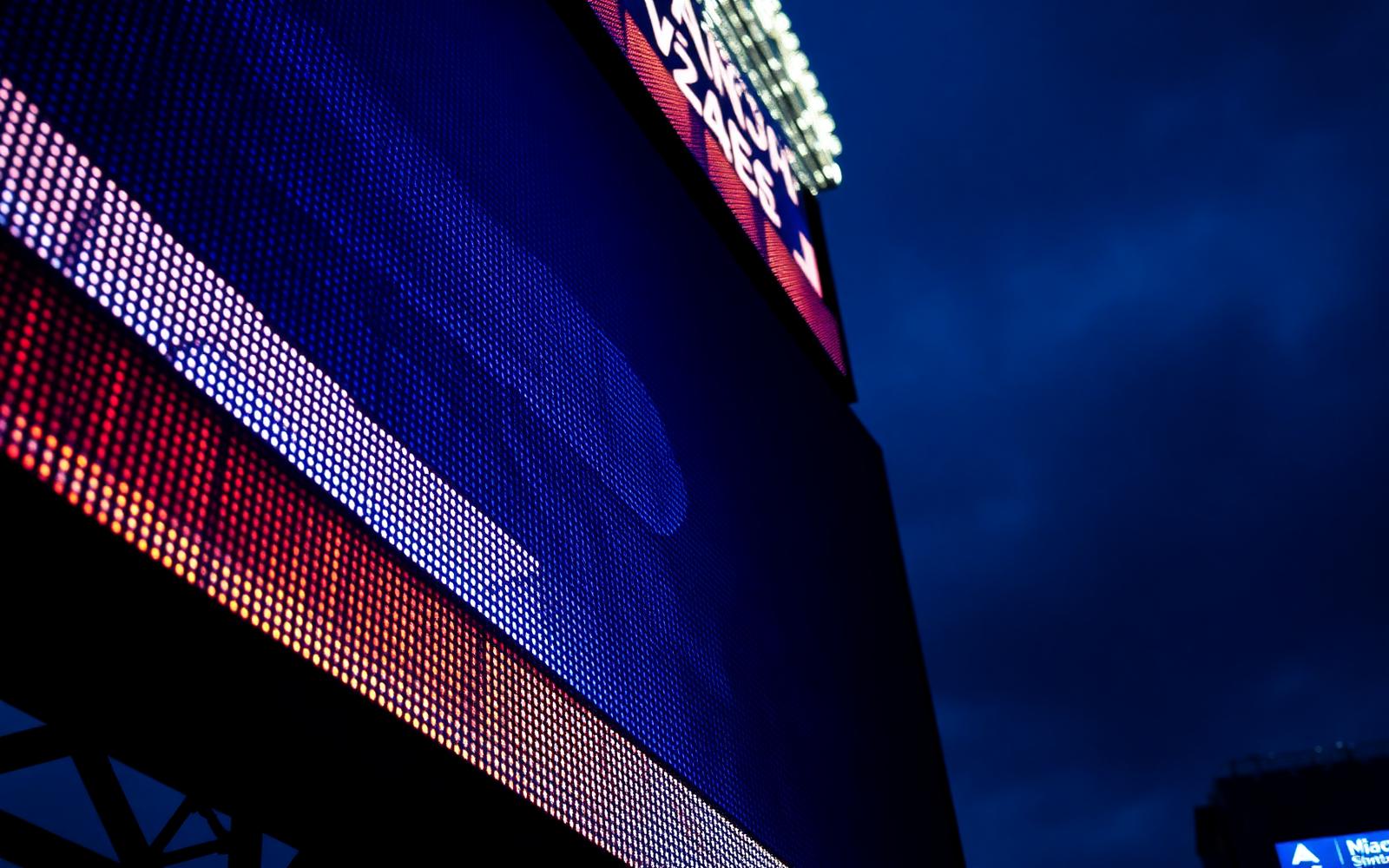 Close-up of an outdoor LED sports scoreboard glowing at dusk